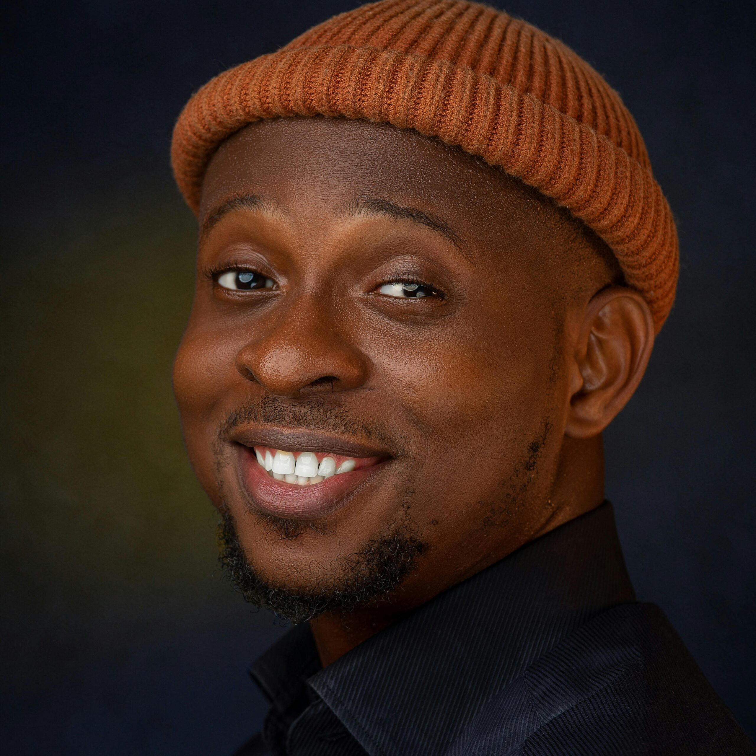 A close-up portrait of a smiling man wearing a beanie, showcasing joy and warmth.