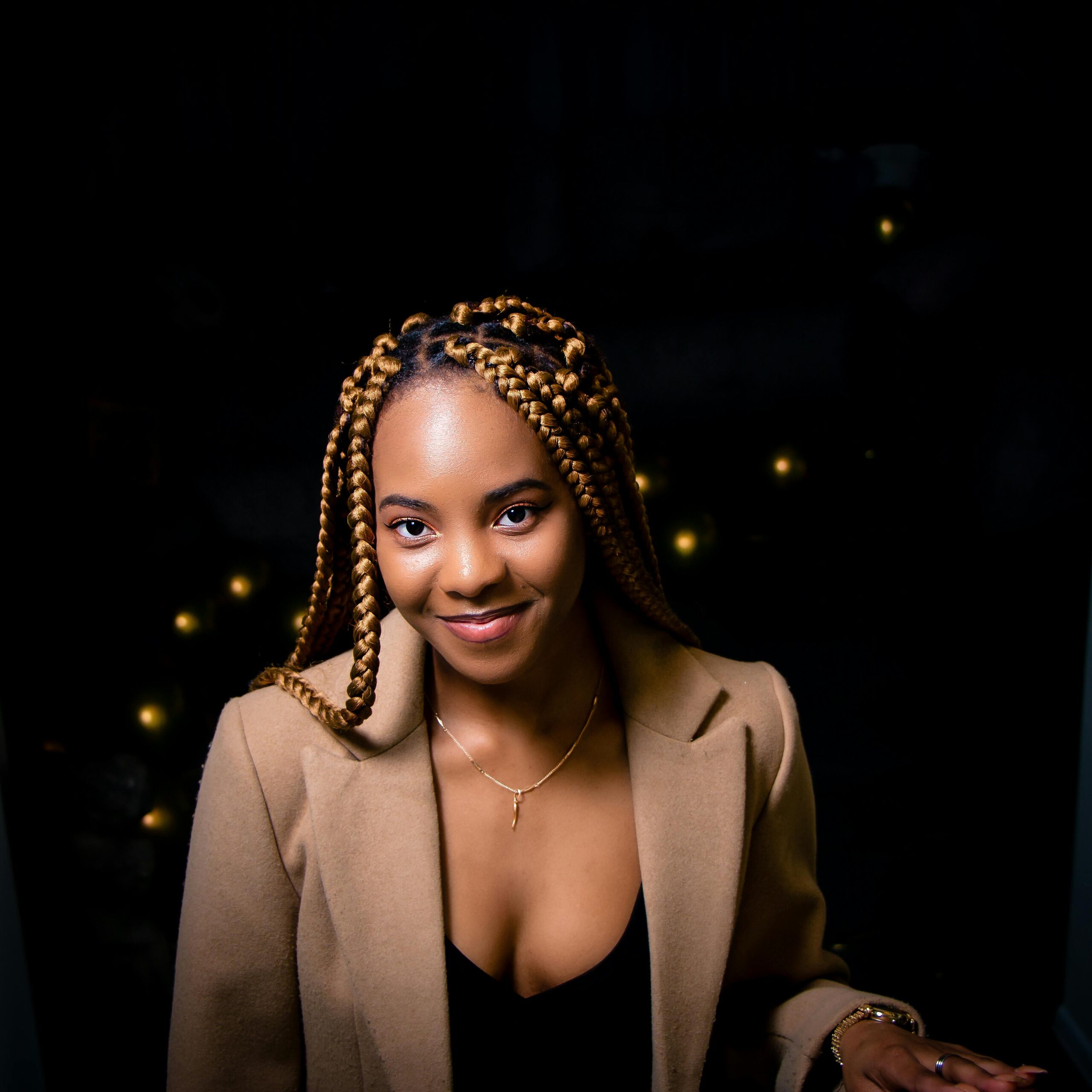 Beautiful portrait of a woman with braided hair, smiling warmly against a dark background.